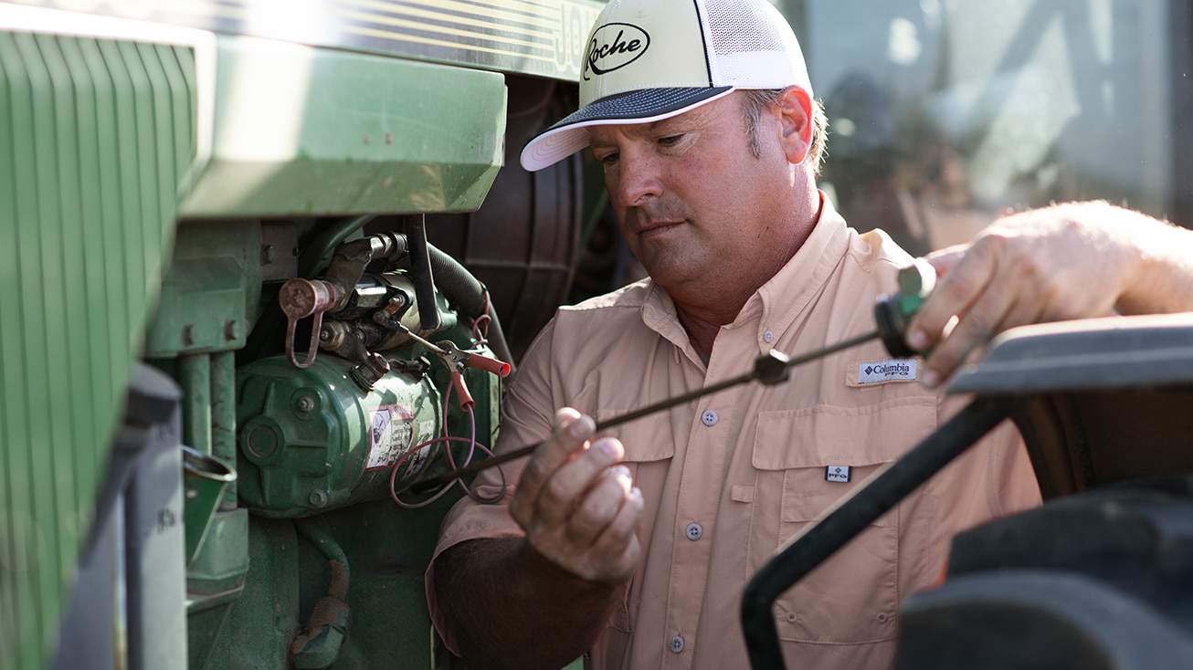 Farmer fixing tractor to reduce production costs.