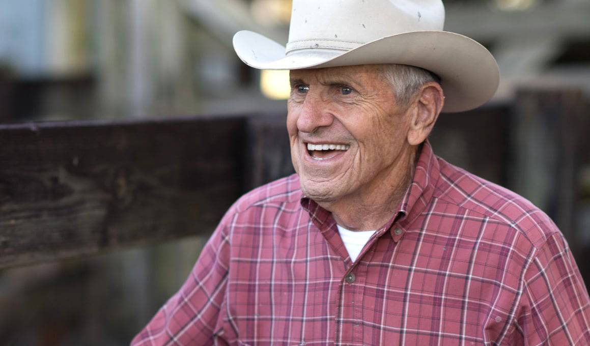 An older man wearing a cowboy hat on a citrus farm.