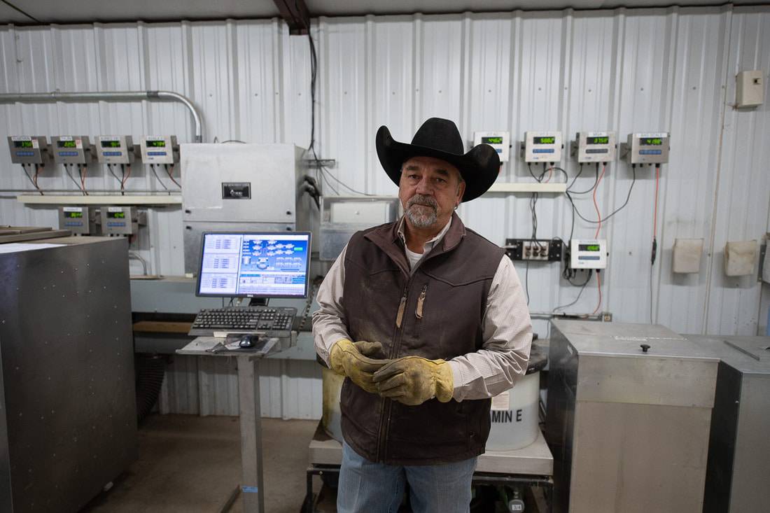 A man in a cowboy hat standing in front of ag equipment.