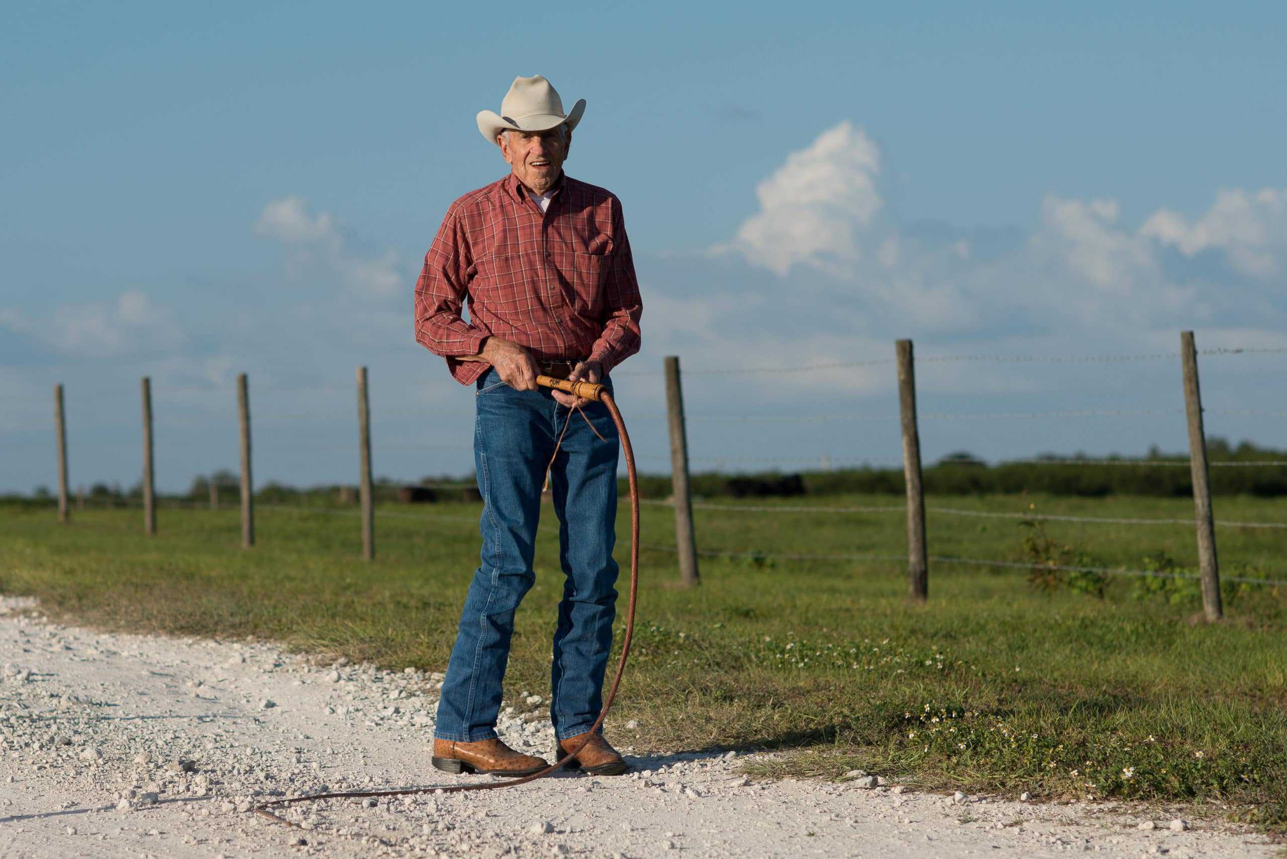 A man in a cowboy hat standing on a dirt road, representing the spirit of family farming.
