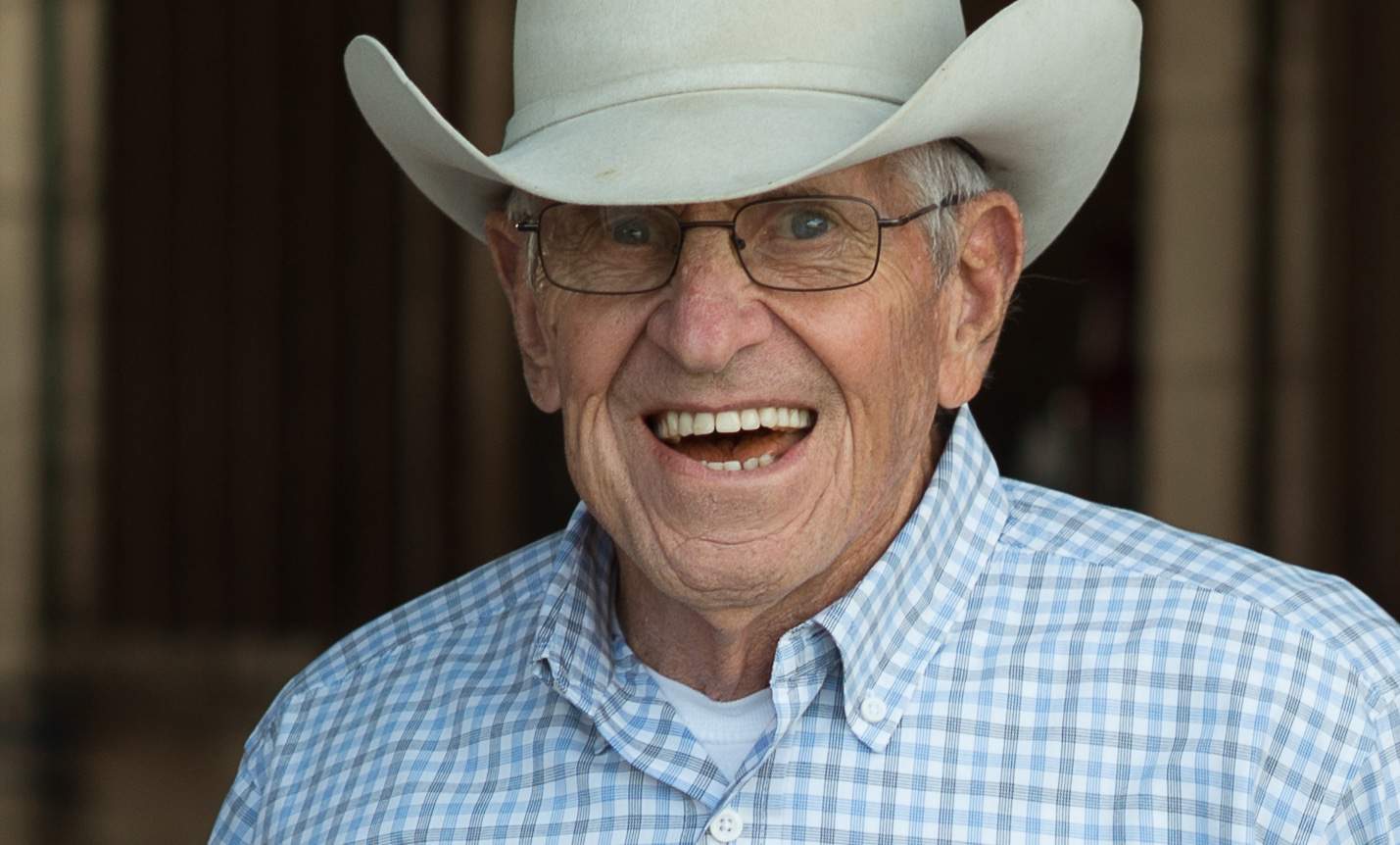 An elderly gentleman in a cowboy hat and glasses enjoying outdoor recreational activities.