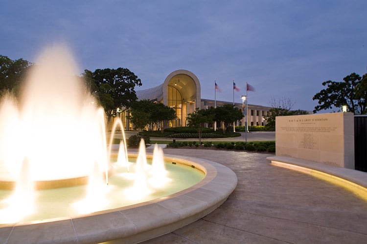 Brian Philpot instructs a fountain in front of a building at dusk.