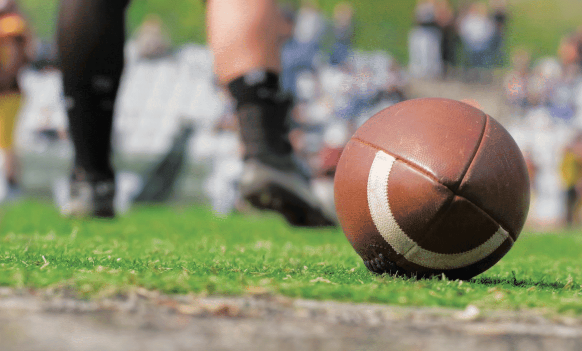 An image of athletes with a football on the field.