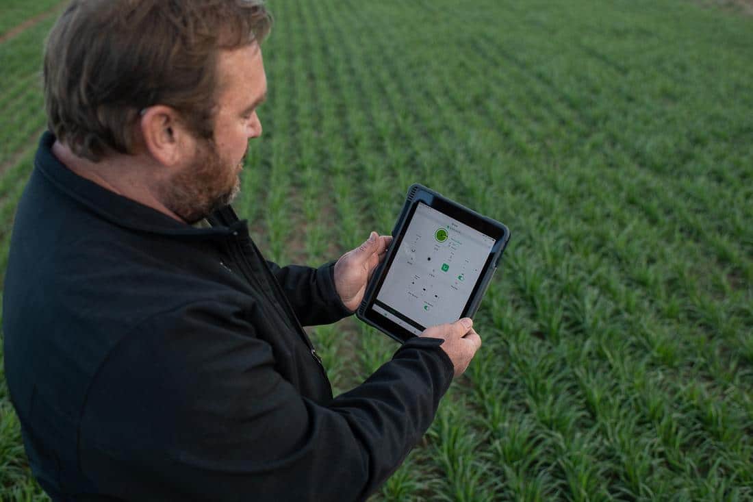An agribusiness professional holding a tablet in a field.
