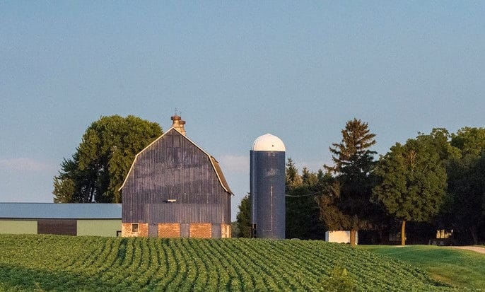 A farm with a blue silo in the middle of a field transformed by AgAmerica.
