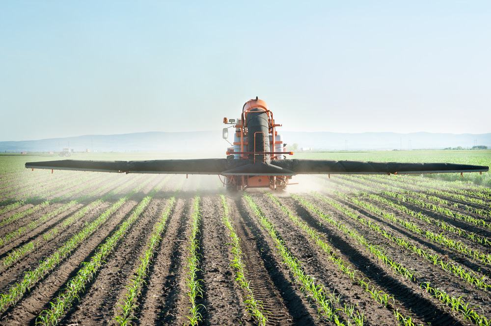 U.S. tractor spraying fertilizer over farmland.