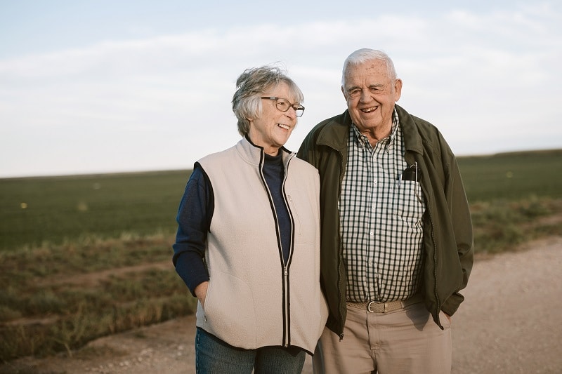 An older Texas couple standing on a dirt road.