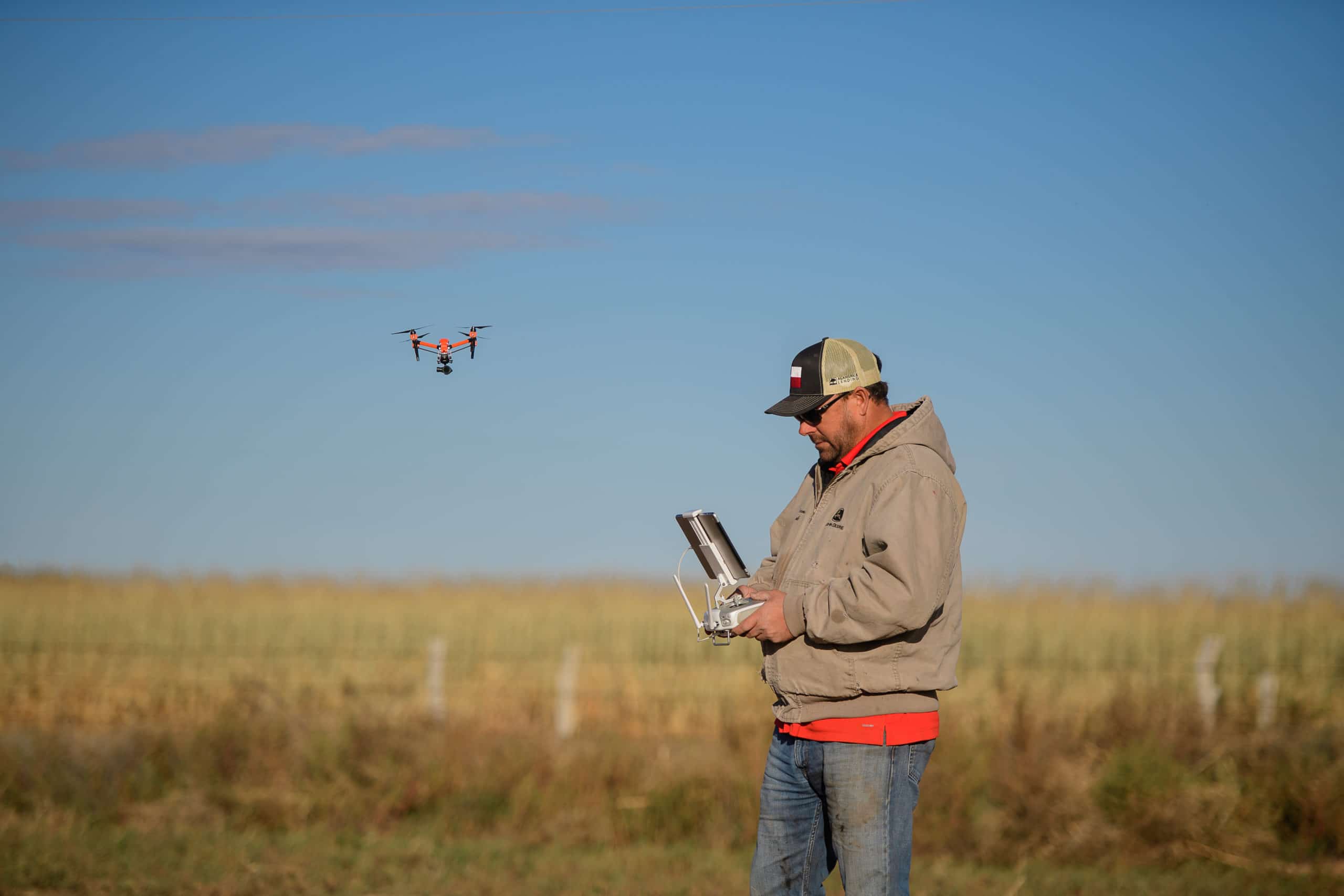 A man standing in a field using drone technology for agriculture purposes.