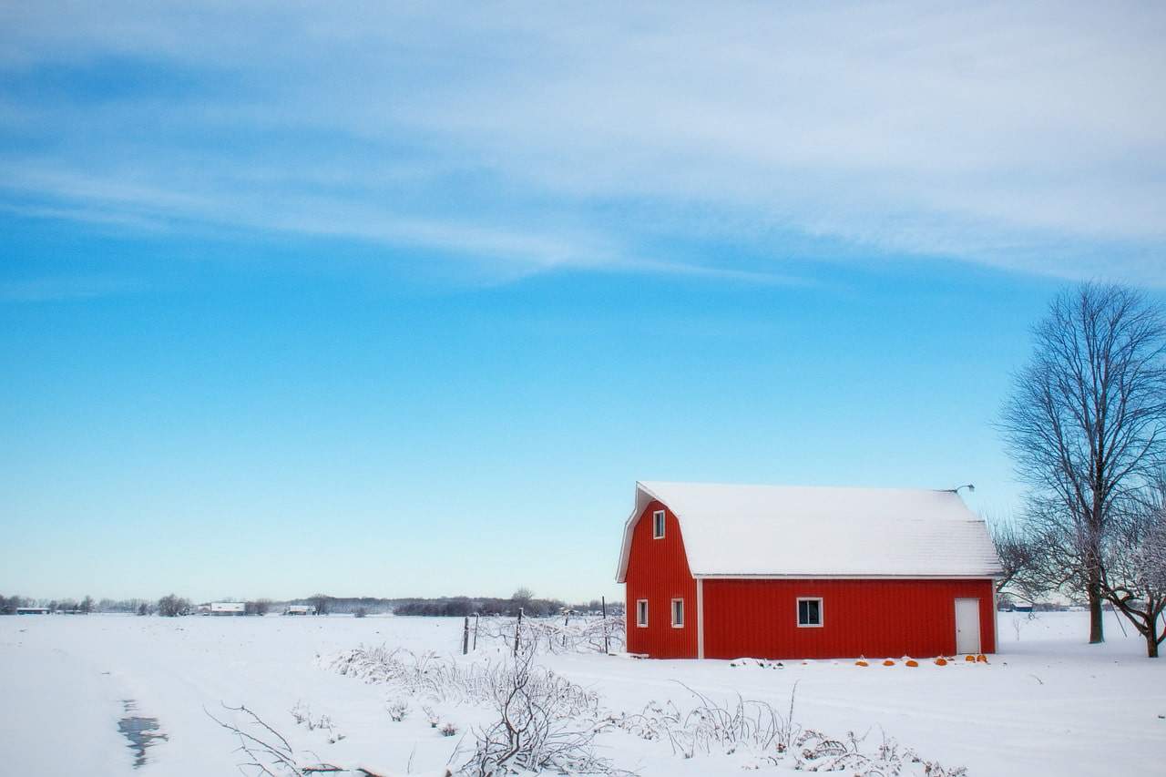 A red barn sits on a snow covered field, meant for ag operating loans.