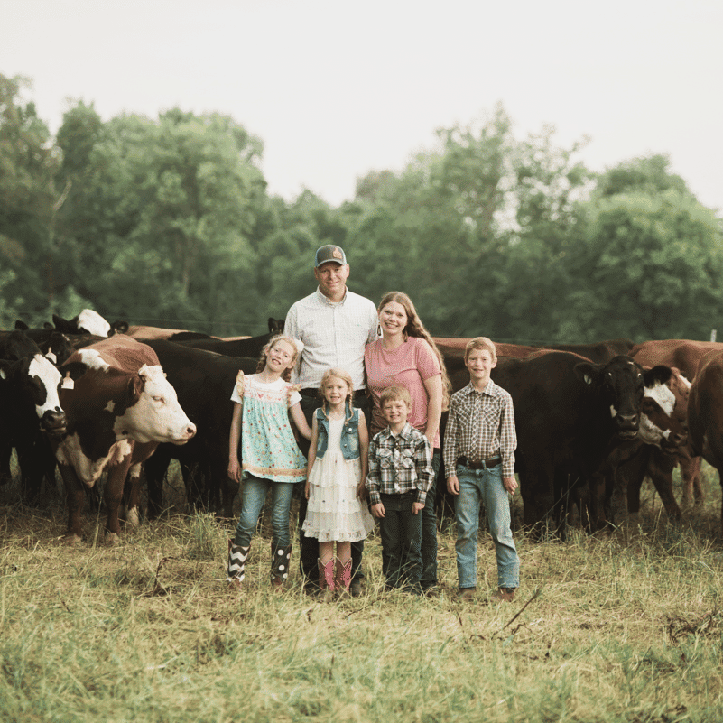 Wesley and Denise Skelton alongside their four children in front of cattle on their Tennessee cattle ranch