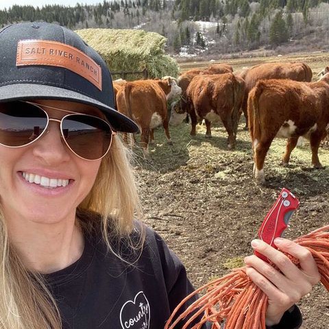 Amy Rhodes standing in front of brown cattle on her Wyoming cattle ranch