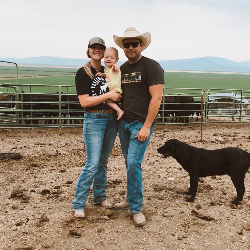 Jordan Johnson standing alongside her husband while holding her child on their Oregon cattle ranch