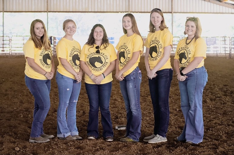 Cassie Perrin standing beside students at an FFA event.