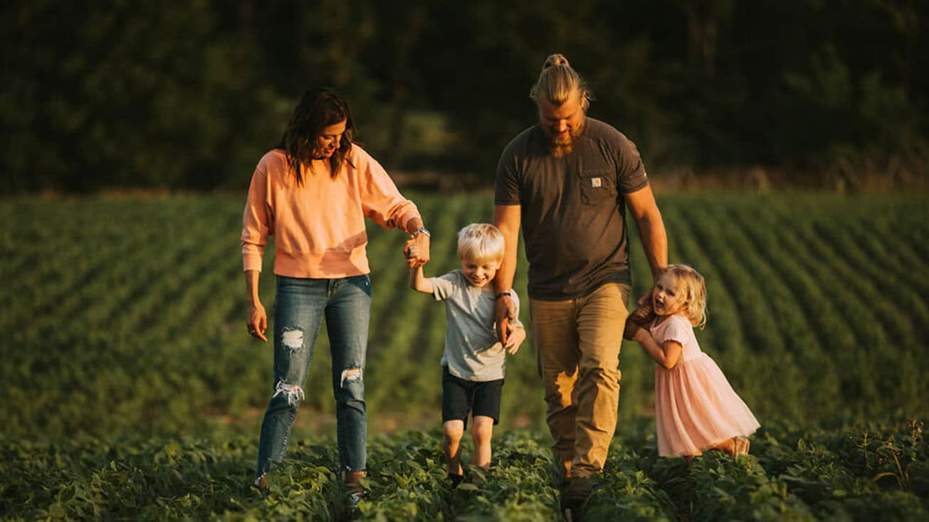 A group of women in agribusiness standing hand in hand in a field.