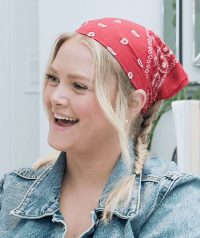 A woman embracing life, sporting a blonde mane, a red bandana, and a denim jacket.