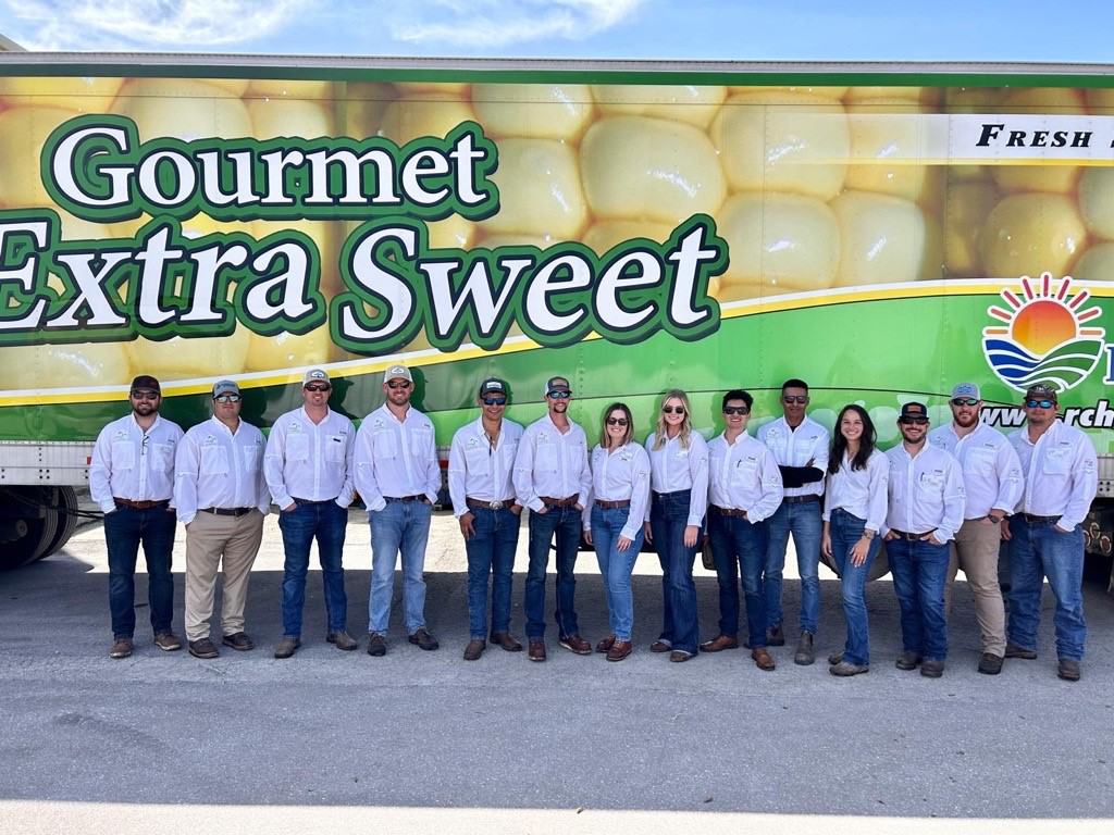 A group of people in white shirts and jeans, featuring Erin Smith, stands in front of a "Gourmet Extra Sweet" truck.